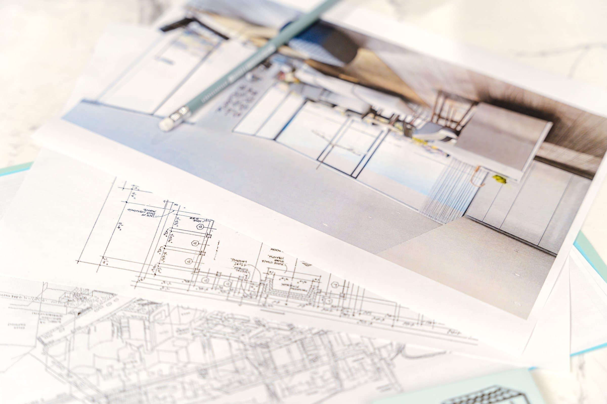 Interior design floor plans, hand drafting and a printed render laid out on a desk